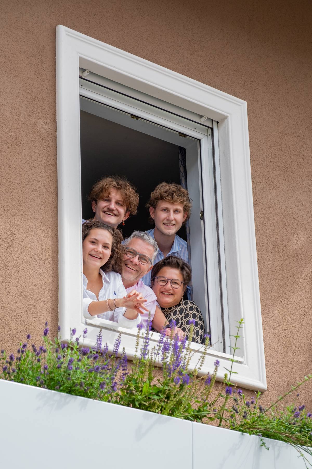 Familie Maier lacht aus einem Fenster des Grünen Hotels zur Post