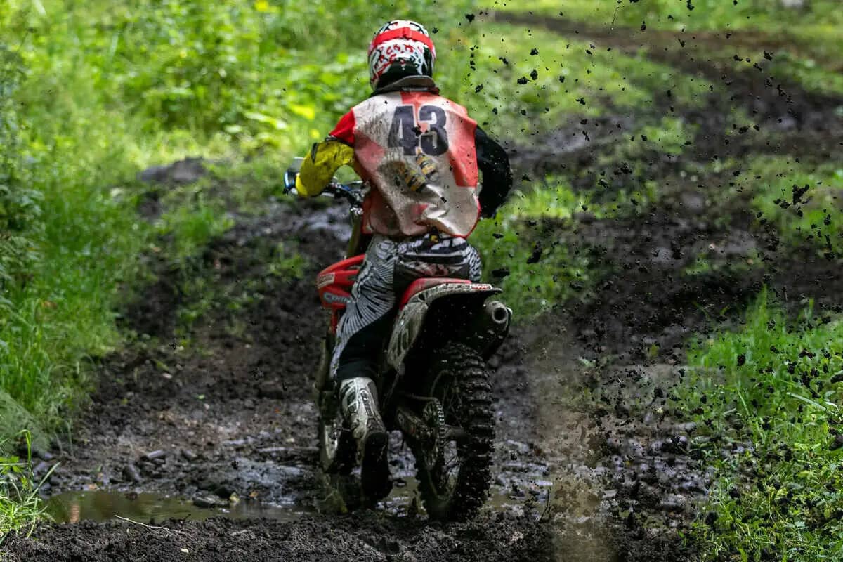 Motocross-Fahrer auf einer schlammigen Strecke im Wald