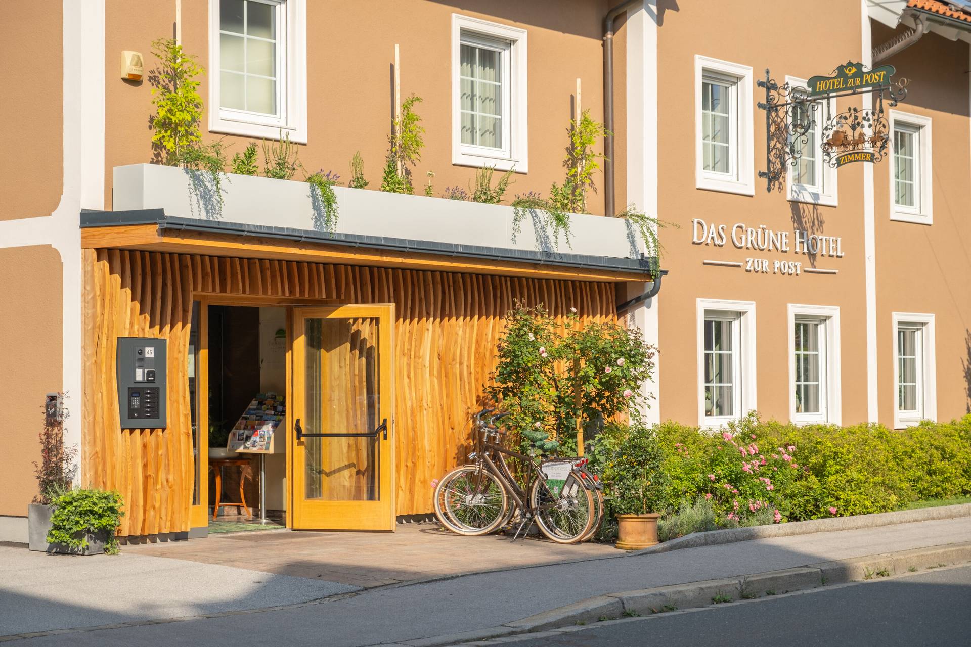 Eingang des Grünen Hotels zur Post mit Holzfassade und Fahrrad