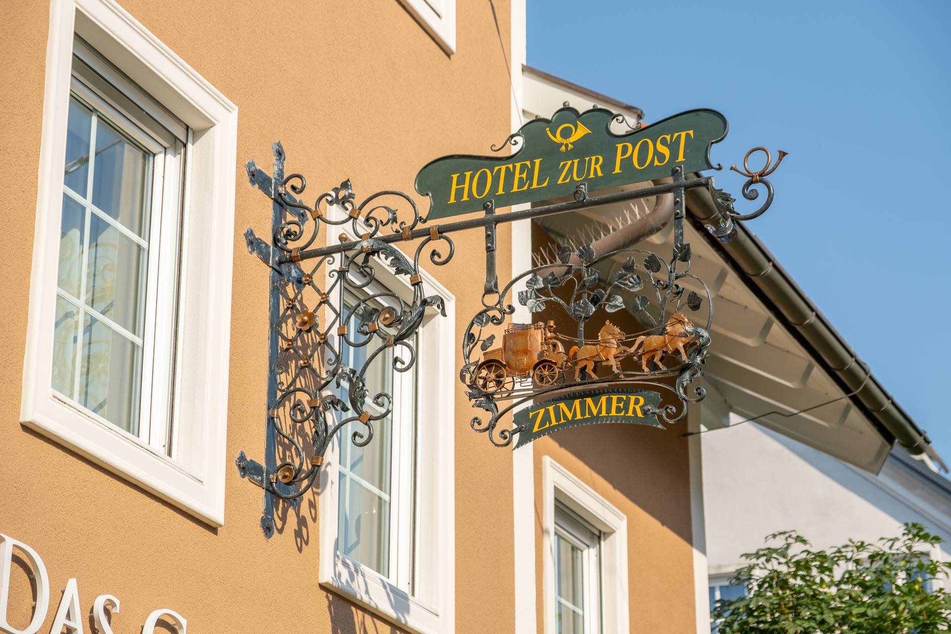 Schmiedeeisernes Schild „Hotel zur Post – Zimmer“ an der Fassade