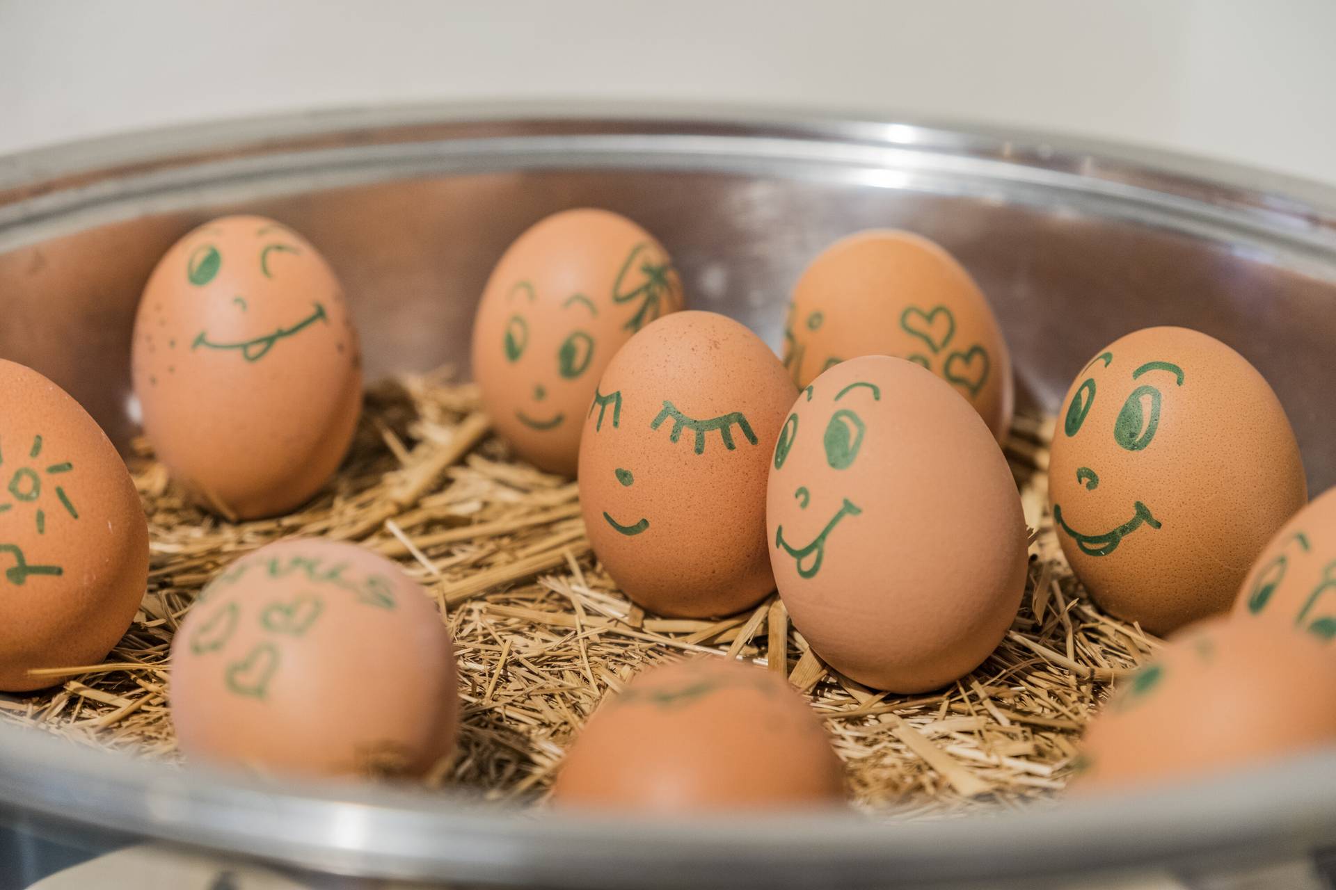 Bemalte Eier mit Gesichtern im Stroh