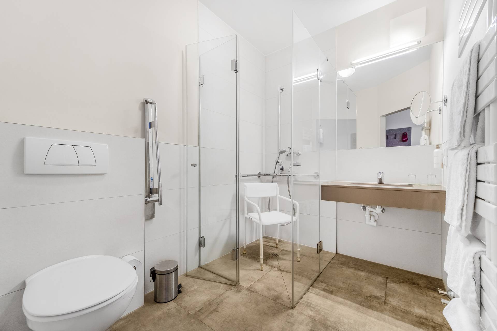 Barrierefreies Badezimmer mit befahrbarer Dusche, Duschsitz und Haltegriffen