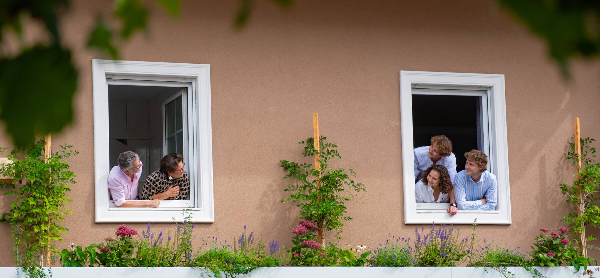 Familie Maier schaut aus zwei Fenstern des Hotels