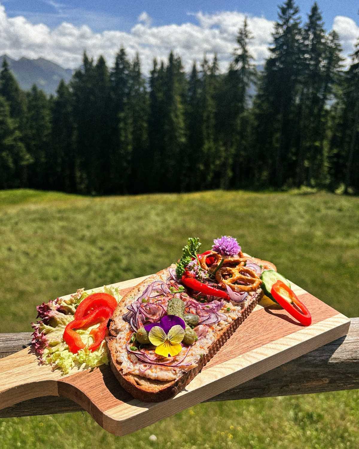 Jausenbrett mit Blüten vor dem Wald