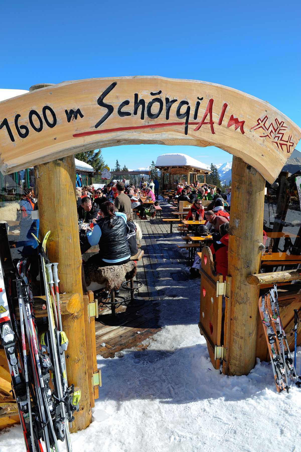 Eingangstor „1600 m Schörgi Alm“ mit Ski davor