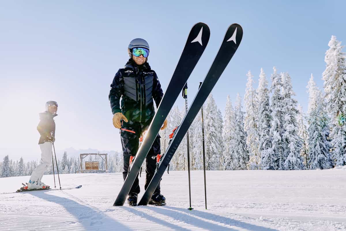 Skifahrer hält Ski aufrecht, tiefe Perspektive, Frau links