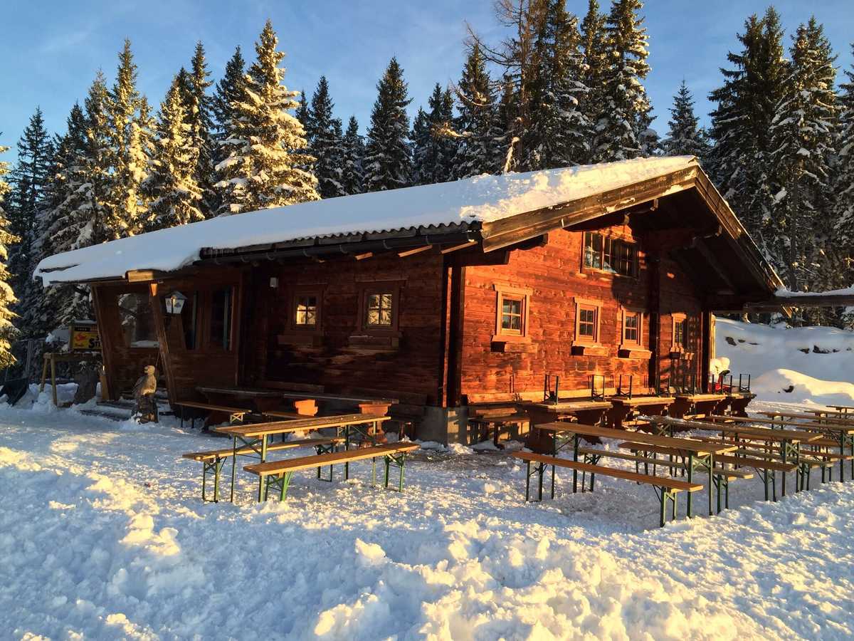 Die Schwaigalm im Abendlicht, Bänke im Schnee, verschneite Fichten